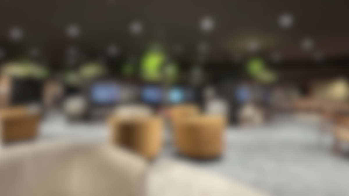Blurred image of a modern lounge with seating and hanging lights.